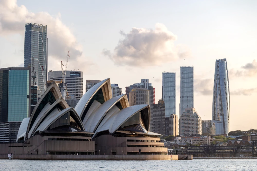 A photo of the iconic Sydney Opera House with tall city buildings in the background, representing a vibrant city destination for a study abroad in Australia experience.